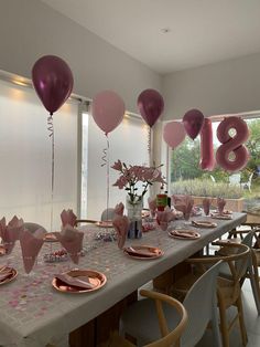 a long table with balloons and plates on it in front of a large window that says 80