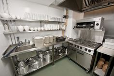 an industrial kitchen with stainless steel appliances and dishes on the counter top, along with pots and pans