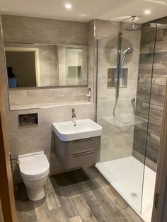 a bathroom with a toilet, sink and shower stall in the middle of the room