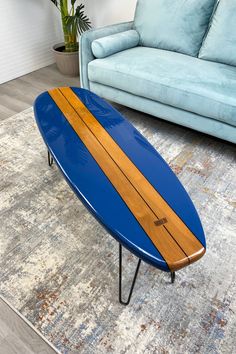 a blue surfboard sitting on top of a wooden table in front of a couch