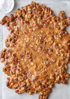 an overhead view of nuts and sauce on a sheet of parchment paper with a bowl of salt in the background