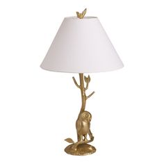 a lamp that has a gold deer on it and a white shade over the base