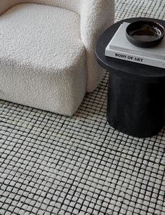 a white chair sitting on top of a rug next to a black table