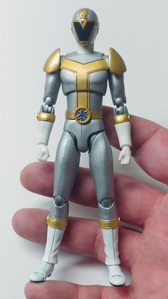 a hand holding a silver and gold action figure