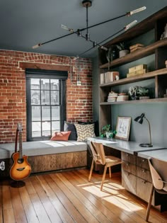 a room with wooden floors, brick walls and a desk in the corner next to a window