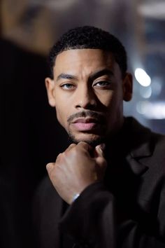 a close up of a person wearing a suit and tie with his hand on his chin