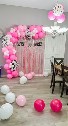 balloons and streamers are scattered on the floor in front of a party backdrop that says let's go girls