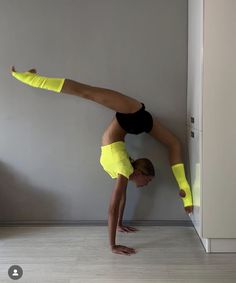 a woman doing a handstand on the floor in front of a white wall