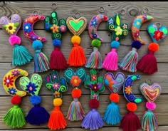 colorful tasselled key chains hanging on a wooden wall with hearts and flowers in the middle