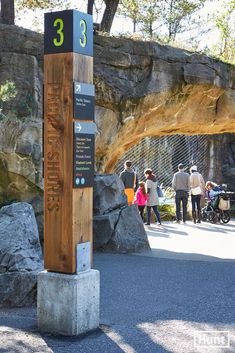 people are walking around in the park near some rocks and an arch with numbers on it