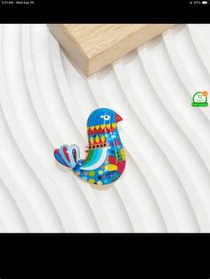 a wooden toy bird sitting on top of a white bed next to a piece of wood