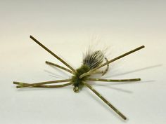 a close up of a green and white spider on a white surface with long legs