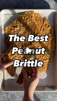 the best peanut brittle is in a plastic container with someone's hand on it