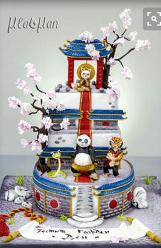 a cake decorated with pandas and flowers on top of a table in front of a gray background