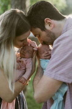 a man and woman are holding their baby girl in the park while she holds her