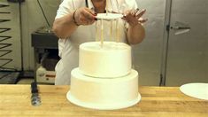 a man holding a knife in front of a white cake