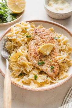 a white plate topped with chicken and pasta next to a bowl of lemonade sauce