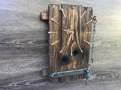 a clock made out of wood with chains hanging from it's sides on a wooden wall