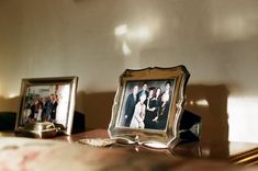 two framed pictures sitting on top of a wooden table