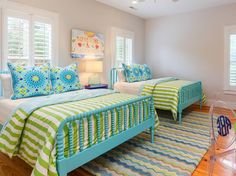 two beds in a bedroom with blue and green bedding