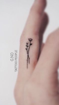 a small flower tattoo on the left hand is shown in black ink, and it's delicate