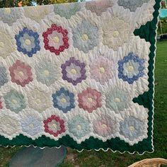 a quilt is hanging on a clothes line in the grass with a basket next to it