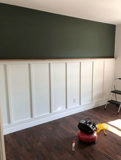 a room with hard wood flooring and green paint on the wall, including a red vacuum