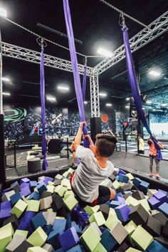 a young boy is playing in an obstacle course at the indoor game show, while others watch