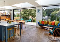 an open kitchen and living room with wood flooring, blue couches and chairs