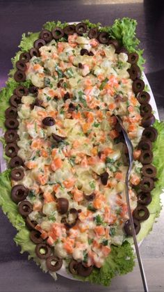 a salad with olives, lettuce and carrots on it