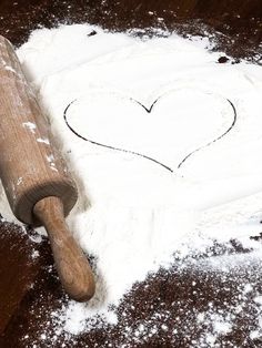 a heart drawn in the snow next to a baseball bat with a wooden handle on it