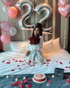 a doll is sitting on a bed with balloons