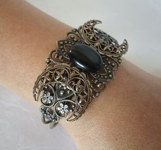 Triple Moon Cuff Bracelet This beautiful brass filigree cuff bracelet has a triple moon design and black cats eye stone setting.  Adjustable. This bracelet can be adjusted by gently squeezing for a smaller size or gently pulling it out for a larger size. wiccan pagan wicca witch godddess witchcraft gothic style Wicca Jewelry, Goddess Bracelet, Gothic Bracelet, Damon And Stefan, Goddess Jewelry, Wiccan Jewelry, Cats Eye Stone, Pagan Jewelry, Black Cat Eyes