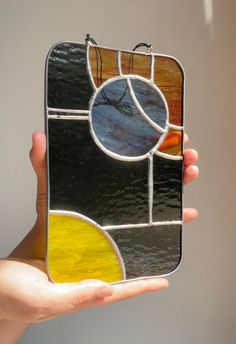 a hand holding up a stained glass case with circles and lines on it's sides