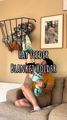 a man sitting on top of a couch holding a baby in his arms with the words hay feeder blanket holder above him