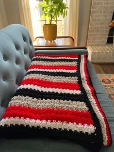 a crocheted blanket sitting on top of a couch next to a potted plant