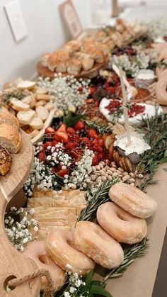 an assortment of pastries and breads on display in a buffet style setting with greenery