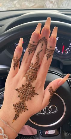 a woman's hand with henna tattoos on it sitting in the driver's seat