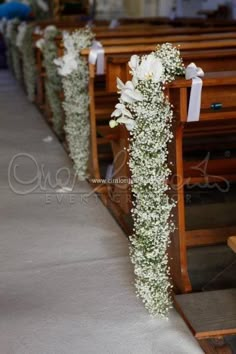 white flowers and greenery decorate the pews of a church