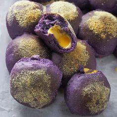 purple desserts with gold sprinkles on them are piled up and ready to be eaten