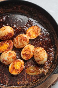 some eggs are cooking in a skillet on the stove top with sauce and seasoning