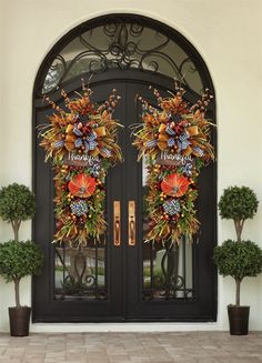 two wreaths on the front door of a house with thanksgiving decorations hanging from them