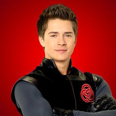 a young man with his arms crossed wearing a black and red hoodie, standing in front of a red background