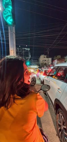 a woman riding a scooter down a street next to traffic lights at night