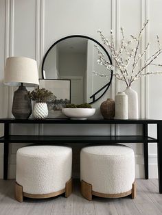 a black table with two stools and a mirror on the wall in front of it