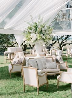 an outdoor setting with chairs, couches and tables covered in white draping