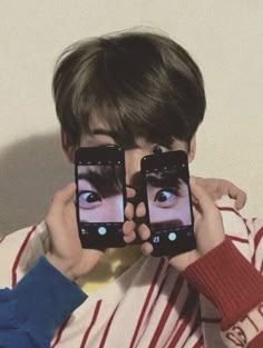 a person holding two cell phones up to their faces with the same image on them