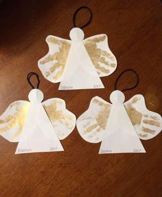 three angel ornaments made out of paper on a table