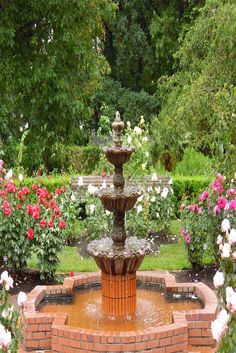 a water fountain surrounded by flowers in a garden