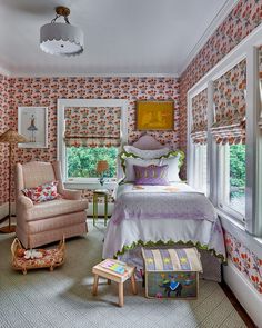 a bedroom with floral wallpaper and pink chair in the corner next to the bed